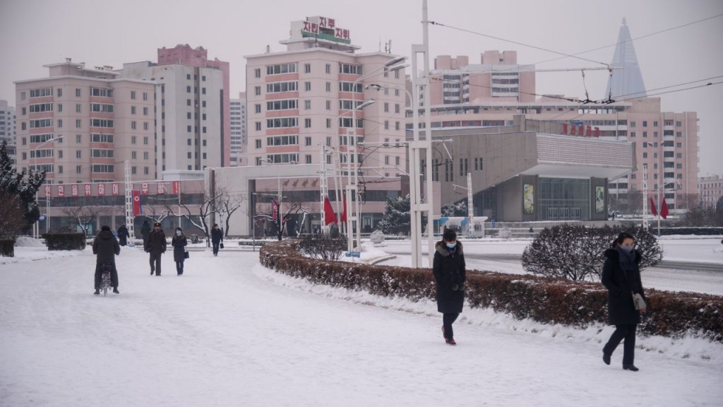 Personas caminan por una calle cubierta de nieve cerca del Arco del Triunfo en Pyongyang el 12 de enero de 2021. (Crédito: KIM WON JIN/AFP/AFP vía Getty Images)