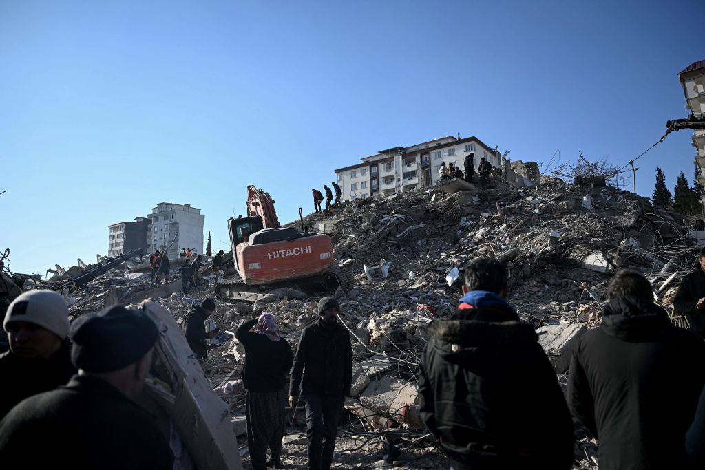 La gente se para entre los escombros de los edificios derrumbados durante las operaciones de búsqueda en Kahramanmaras, el 9 de febrero de 2023, tres días después de que un terremoto de magnitud 7,8 azotara el sureste de Turquía. (Crédito: OZAN KOSE/AFP vía Getty Images)
