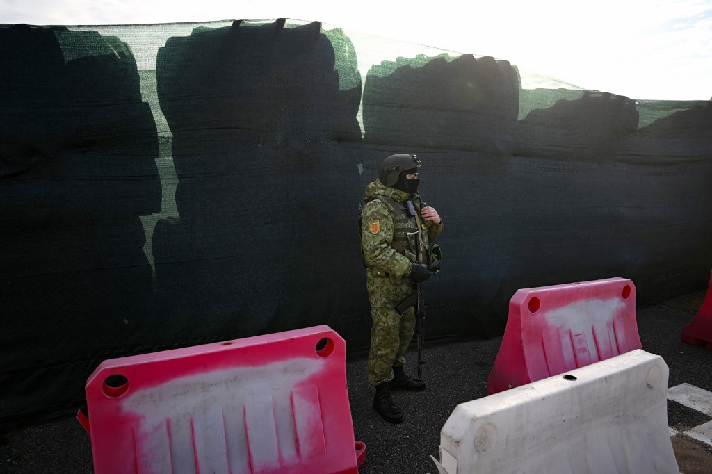 Un guardia fronterizo bielorruso vigila de pie junto a una barricada hecha con neumáticos de camión en el paso fronterizo de Dyvin, entre Belarús y Ucrania, en la región de Brest, el 15 de febrero. (Crédito: Natalia Kolesnikova/AFP/Getty Images)