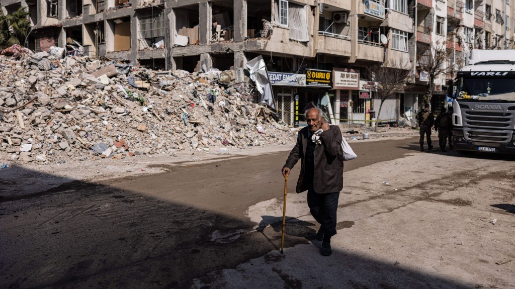 Un hombre camina junto a edificios derrumbados en la ciudad de Antakya, en la provincia de Hatay, en el sur de Turquía, el 22 de febrero de 2023. (Crédito: SAMEER AL-DOUMY/AFP vía Getty Images)