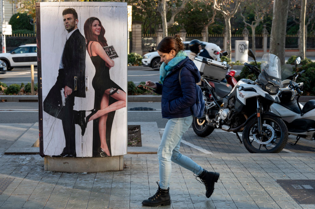 Una mujer camina en Barcelona ante un cartel de una publicidad. (JOSEP LAGO/AFP via Getty Images)