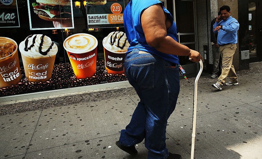 Una mujer camina frente a un cartel de bebidas azucaradas en Brooklyn, Nueva York, en 2013. (Crédito: Spencer Platt/Getty Images)
