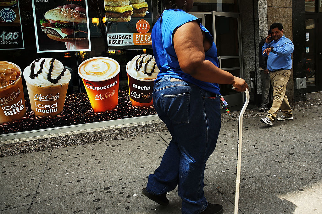 Una mujer camina frente a un cartel de bebidas azucaradas en Brooklyn, Nueva York, en 2013. (Crédito: Spencer Platt/Getty Images)