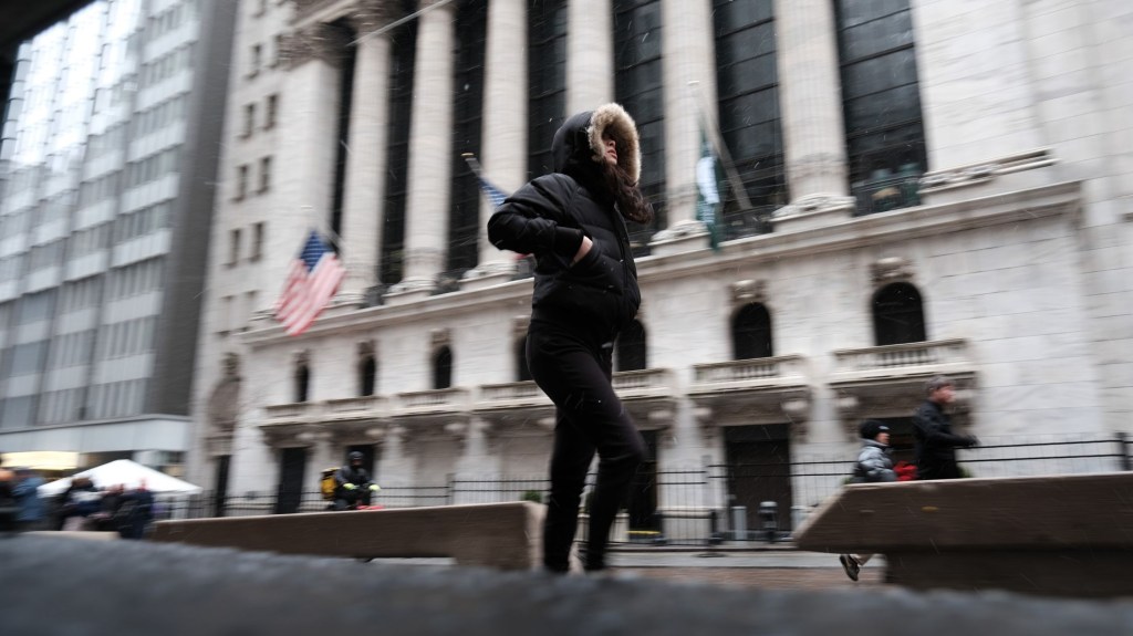 Personas caminan por el bajo Manhattan junto a la Bolsa de Nueva York (NYSE) bajo una ligera nevada el 14 de marzo de 2023 en la ciudad de Nueva York. Gran parte del noreste está siendo azotada por una tormenta invernal tardía que trae viento, lluvia y nieve a muchas zonas. (Crédito: Spencer Platt/Getty Images)