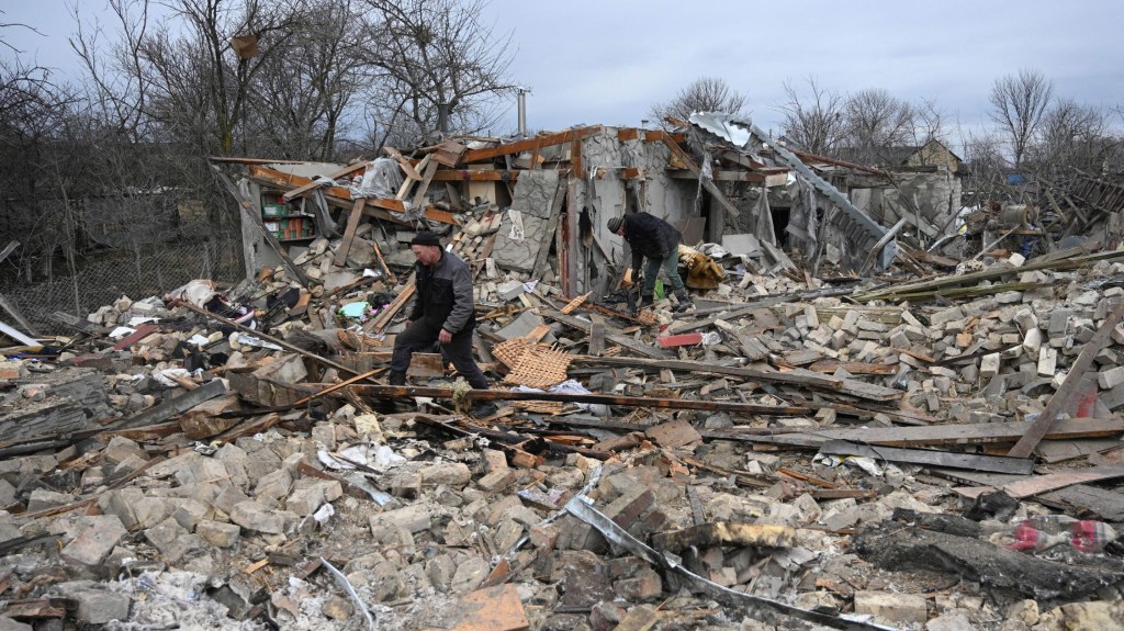 Varias personas buscan entre los escombros de una casa tras un ataque ruso en el pueblo de Velyka Vilshanytsia, a unos 50 km de Lviv, el 9 de marzo de 2023. (Crédito: YURIY DYACHYSHYN/AFP vía Getty Images)