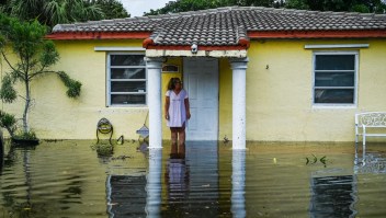 Una mujer mira mientras permanece fuera de una casa inundada después de fuertes lluvias en Fort Lauderdale, Florida, el 13 de abril de 2023.