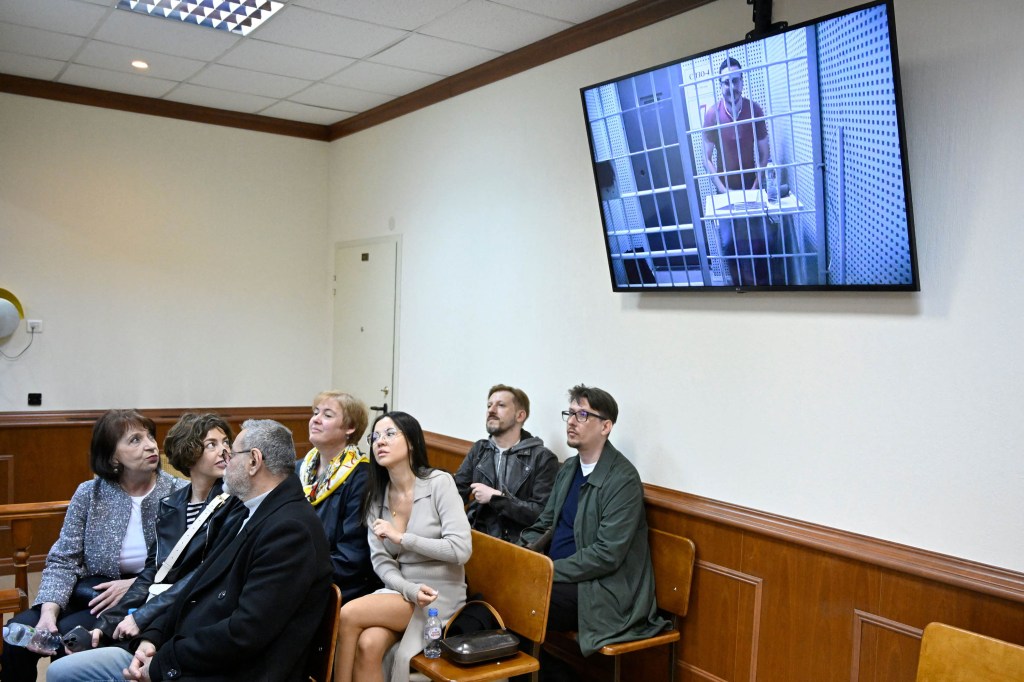 Ilya Yashin aparece en una pantalla a través de una conexión de video durante una audiencia en la que se estudia un recurso contra su condena de prisión, mientras sus partidarios observan desde una sala del tribunal en Moscú, Rusia, el 19 de abril. (Crédito: Alexander Nemenov/AFP/Getty Images)