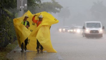 Trabajadores utilizan una lona para protegerse de la lluvia el 12 de abril de 2023 en Dania Beach, Florida. Fuertes lluvias pasaron por el área del sur de Florida causando algunas inundaciones en el área. (Crédito: Joe Raedle/Getty Images)