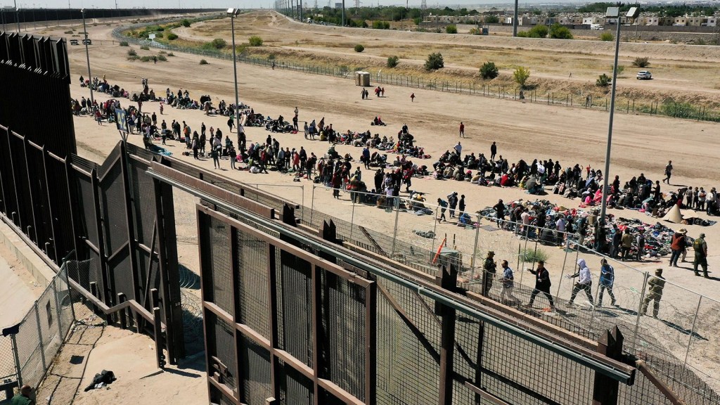 Una imagen aérea muestra a migrantes esperando junto al muro fronterizo para entregarse a los agentes de la Patrulla Fronteriza del CBP para la tramitación de solicitudes de inmigración y asilo tras cruzar el río Grande hacia EE.UU. en El Paso, Texas, el 10 de mayo. (Foto: Patrick T. Fallon/AFP/Getty Images)