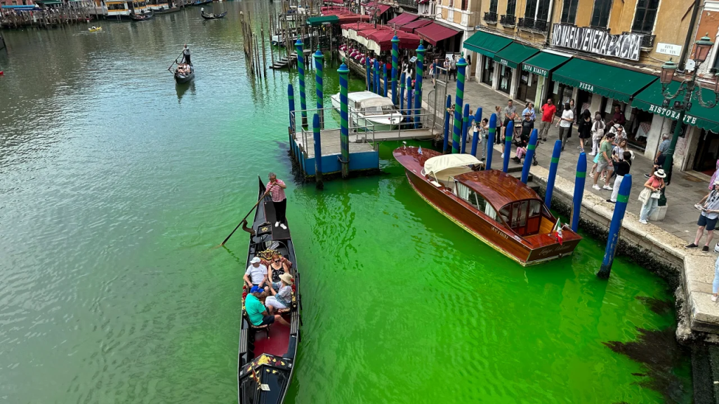 Una góndola cruza el histórico Gran Canal de Venecia mientras una mancha de líquido verde fluorescente se extiende en él, el domingo 28 de mayo de 2023. (Foto: Luigii Costantini/AP)