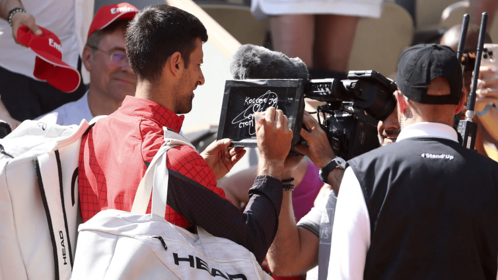 Djokovic writes a message on the lens of a television camera at Roland-Garros.  (Photo: Jean Catuffe/Getty Images)