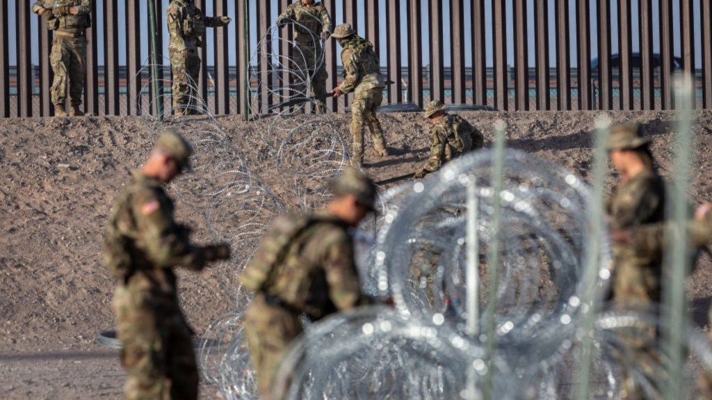 Soldados de la Guardia Nacional de Texas desenrollan alambre de púas alrededor de un campamento de inmigrantes improvisado ubicado entre el Río Grande y la cerca fronteriza entre Estados Unidos y México el 10 de mayo de 2023 en El Paso, Texas. (Foto: John Moore/Getty Images)