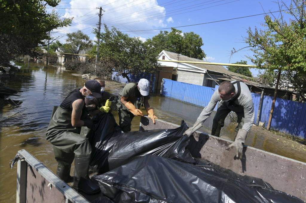 Voluntarios y trabajadores municipales recuperan un cadáver de una casa inundada en la ciudad ocupada por Rusia de Hola Prystan, Ucrania, el 16 de junio, mientras las aguas retroceden tras el colapso de la presa de Nova Kakhovka. (Foto: Stringer/Anadolu Agency/Getty Images)