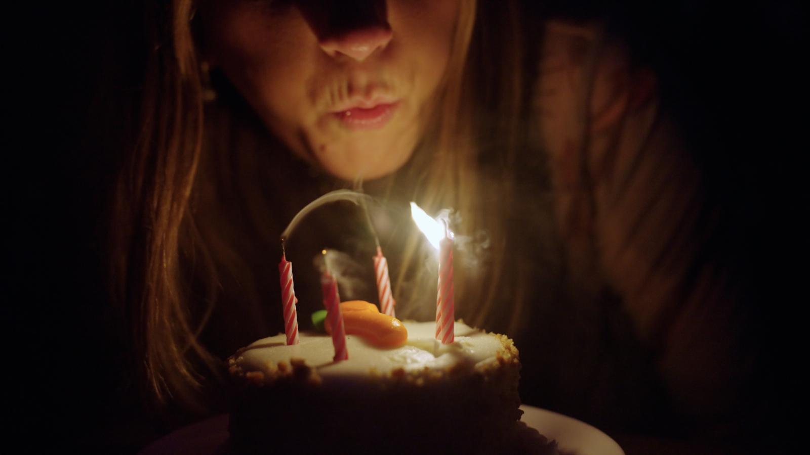 La chica apaga las velas del pastel de cumpleaños. Una chica apaga