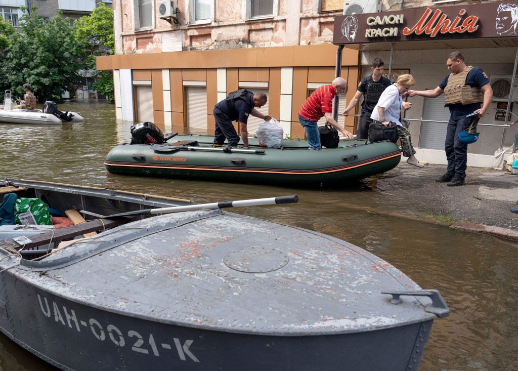 Fuerzas de seguridad ucranianas ayudan a desembarcar a residentes locales de un bote durante una evacuación de una zona inundada en Jersón el 8 de junio. (Foto: Aleksey Filippov/AFP/Getty Images)