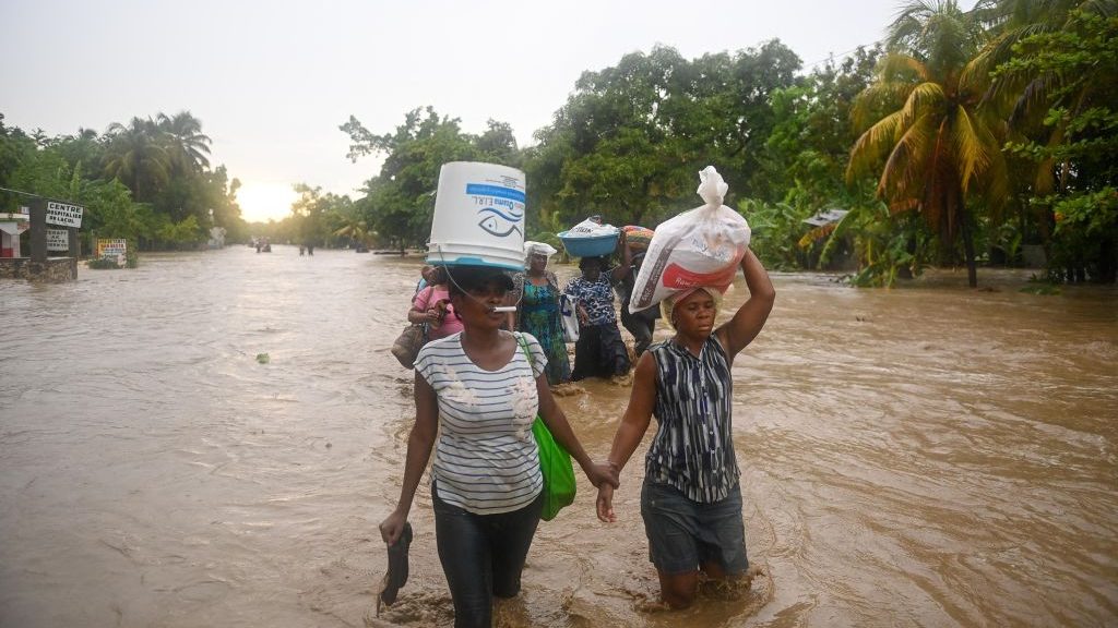 Residentes cruzan la sumergida Ruta Nacional número 2 al oeste del Puerto Príncipe, Haití, el 3 de junio de 2013, durante las fuertes lluvias. (Crédito: by RICHARD PIERRIN/AFP via Getty Images)