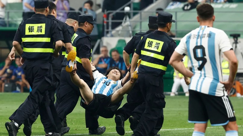 Agentes de seguridad sacan del campo al joven invasor durante un partido en el Estadio de los Trabajadores en Beijing, China, el 15 de junio.  (Crédito: Thomas Peter/Reuters)