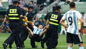Agentes de seguridad sacan del campo al joven invasor durante un partido en el Estadio de los Trabajadores de Beijing, China, el 15 de junio. (Crédito: Thomas Peter/Reuters)