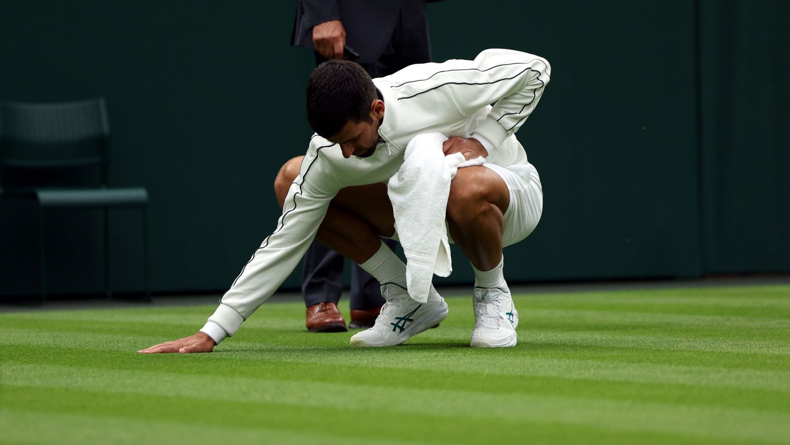 Novak Djokovic tends to the grass on center court during his first round win against Pedro Cachín at Wimbledon.  (Neil Hall/EPA-EFE/Shutterstock)