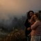 Varios vecinos observan un incendio forestal que se aproxima al pueblo de Zambujeiro, en Cascais (Portugal), el 25 de julio.