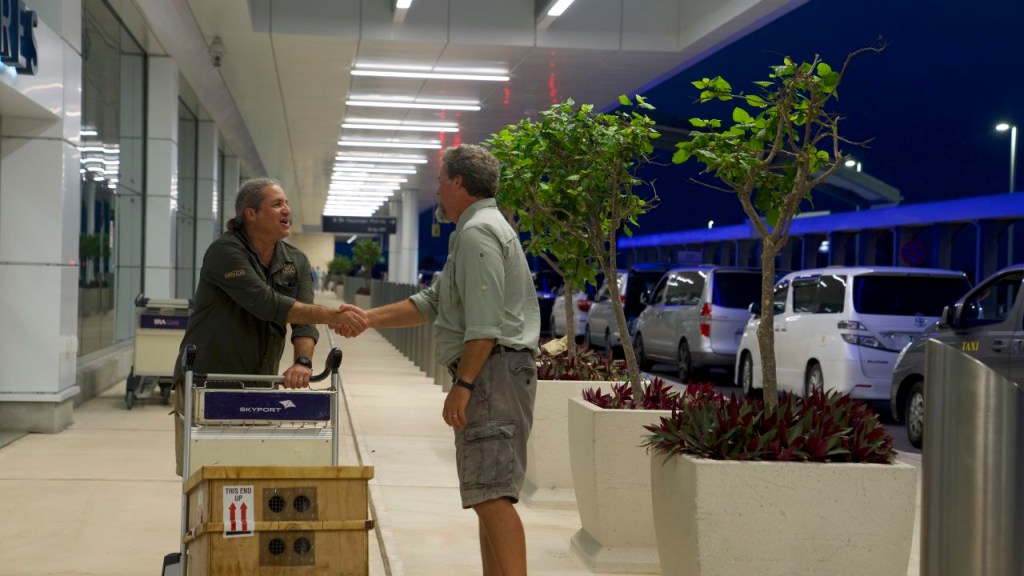 Gerardo García (izquierda) saluda al ambientalista Mark Outerbridge cuando llega a las Bermudas con una caja de caracoles en peligro de extinción.  (Crédito: Sandy Thin/CNN)