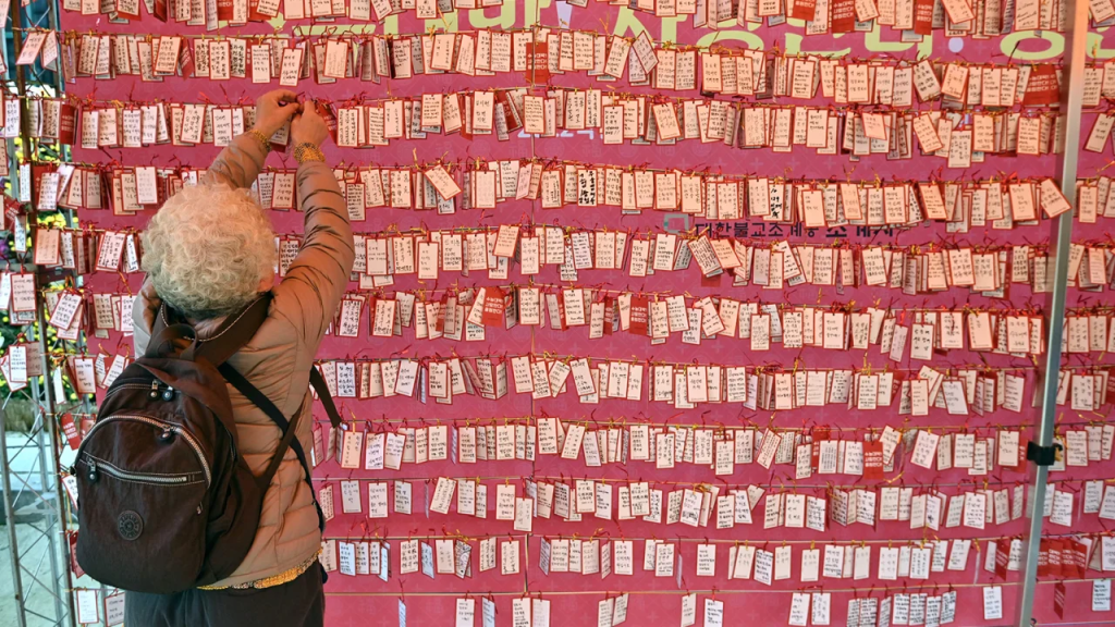 Una mujer adhiere una tarjeta con su nombre deseando buenos resultados para los estudiantes en el examen de ingreso a la universidad en Corea del Sur, en un templo en Seúl el 18 de noviembre de 2021. (Foto: Jung Yeon-je/AFP/Getty Images/Archivo)