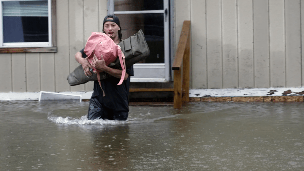 Un hombre transporta sus pertenencias a través de las aguas de una casa en Bridgewater, Vermont, el lunes. (Foto: Hasan Jamali/AP)