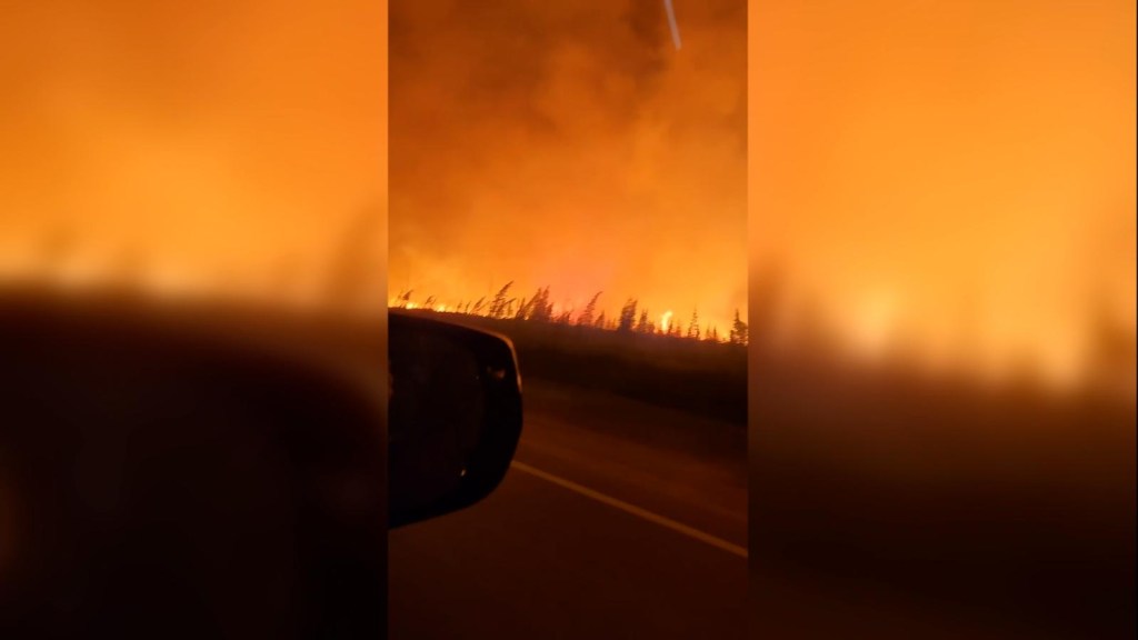 Un auto escapa de las llamas en los incendios de Canadá