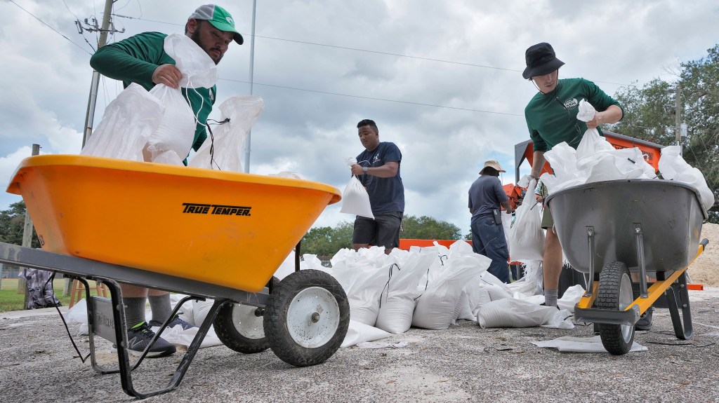 Miembros del Departamento de Parques y Ocio de Tampa ayudan a los residentes a embolsar arena este lunes. (Foto: Chris O'Meara/AP)