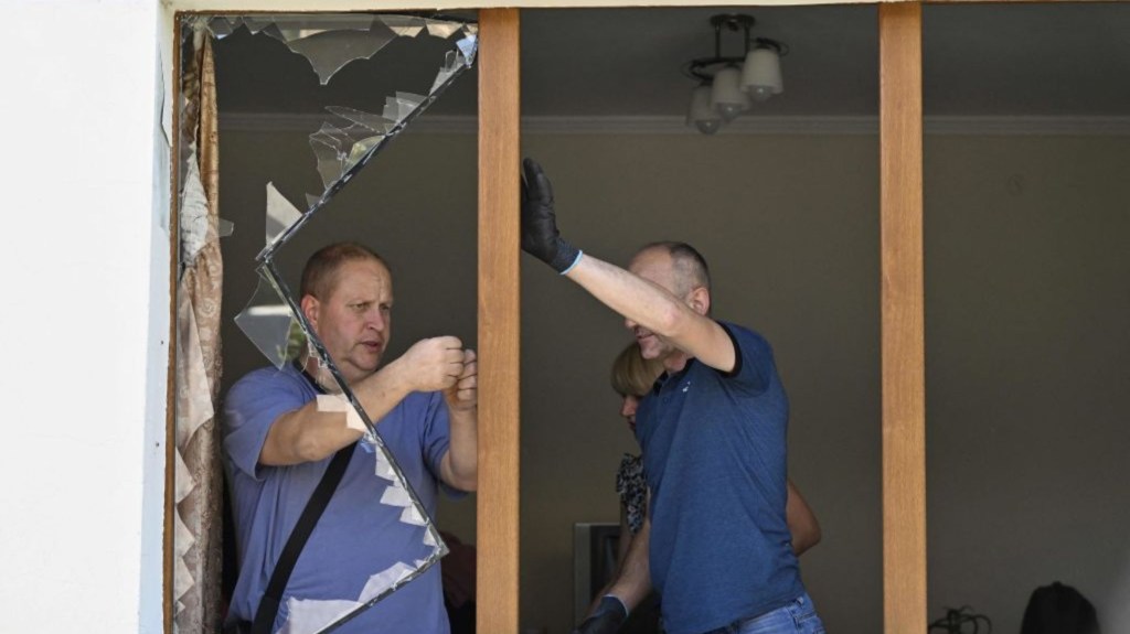 Residentes locales retiran los cristales rotos de la ventana de un edificio residencial tras el impacto de un misil en la ciudad de Lviv, en el oeste de Ucrania, el 15 de agosto de 2023, en medio de la invasión rusa en Ucrania. (Foto: GENYA SAVILOV/AFP vía Getty Images)