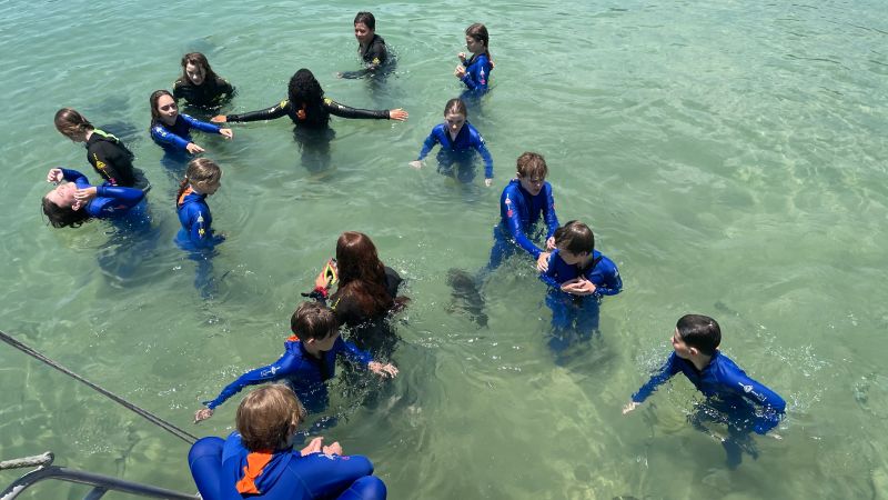 En las cálidas aguas de la costa de Queensland, en Australia, estudiantes de la Belgian Gardens State School aprenden sobre el maravilloso entorno coralino local durante el Día del Llamado a la Tierra 2022.