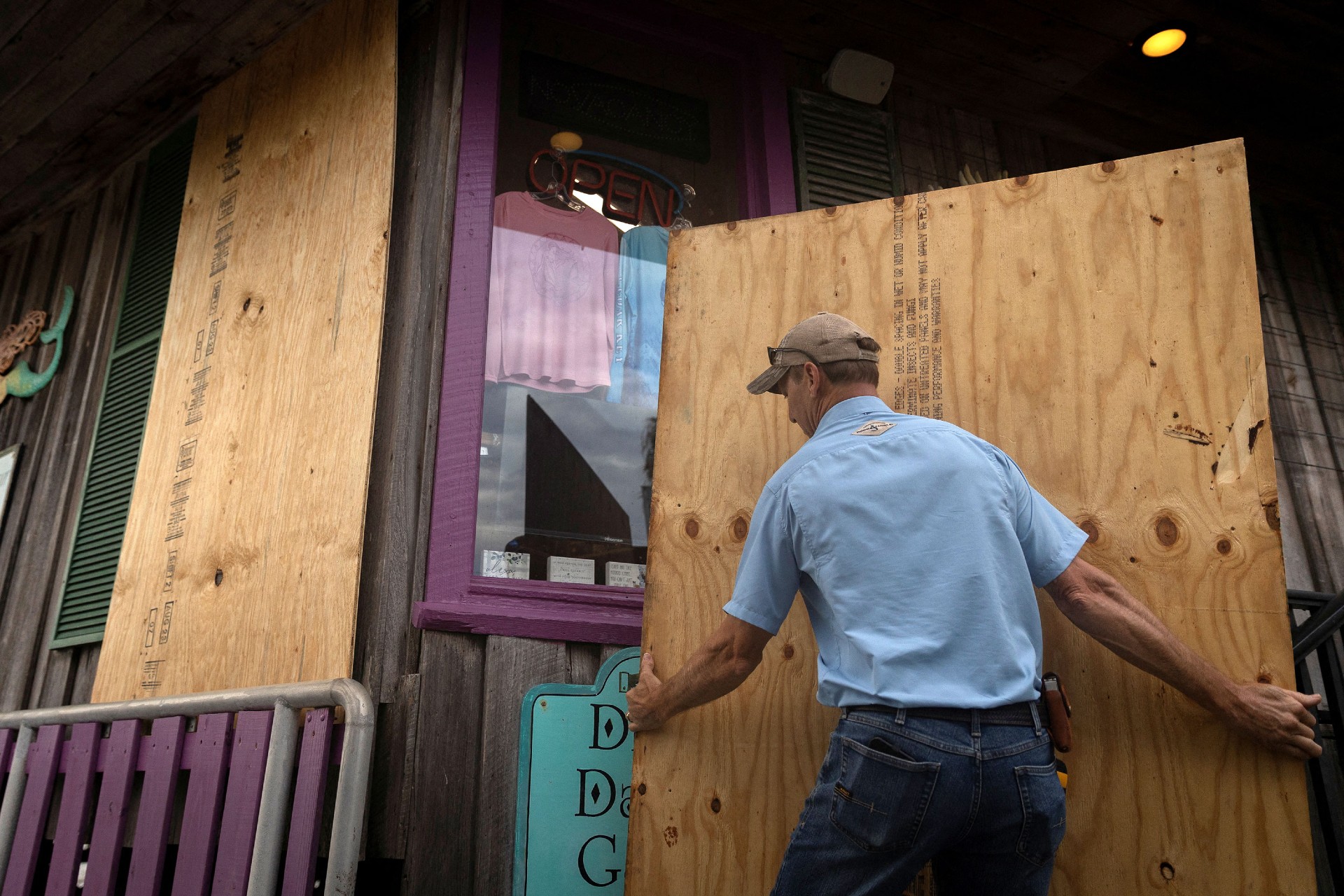 Un hombre coloca madera enchapada frente a una tienda en Cedar Key el martes. (Marco Bello/Reuters)