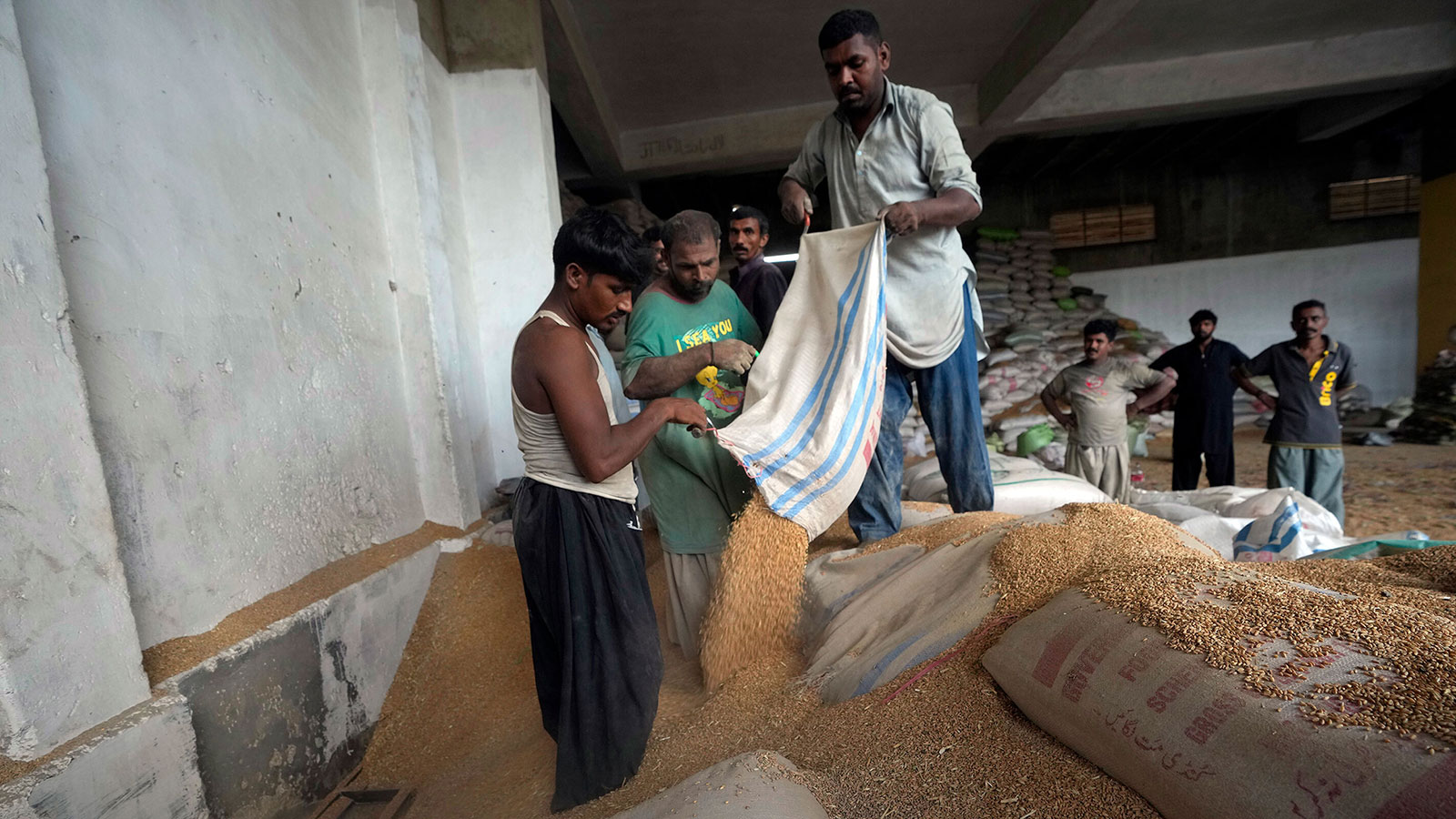 Trabajadores paquistaníes clasifican el trigo en un almacén en Karachi, Pakistán, el 26 de julio. (Fareed Khan/AP/FILE)