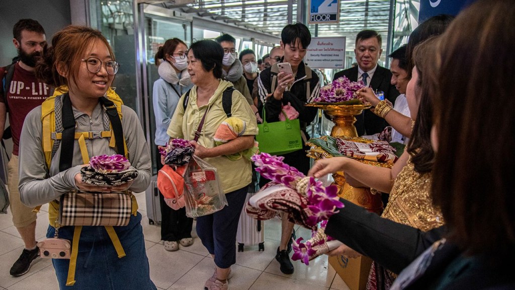 Funcionarios tailandenses reciben a turistas chinos con regalos en el aeropuerto internacional Suvarnabhumi de Bangkok el 25 de septiembre de 2023. (Peerapon Boonyakiat/SOPA Images/LightRocket/Getty Images)