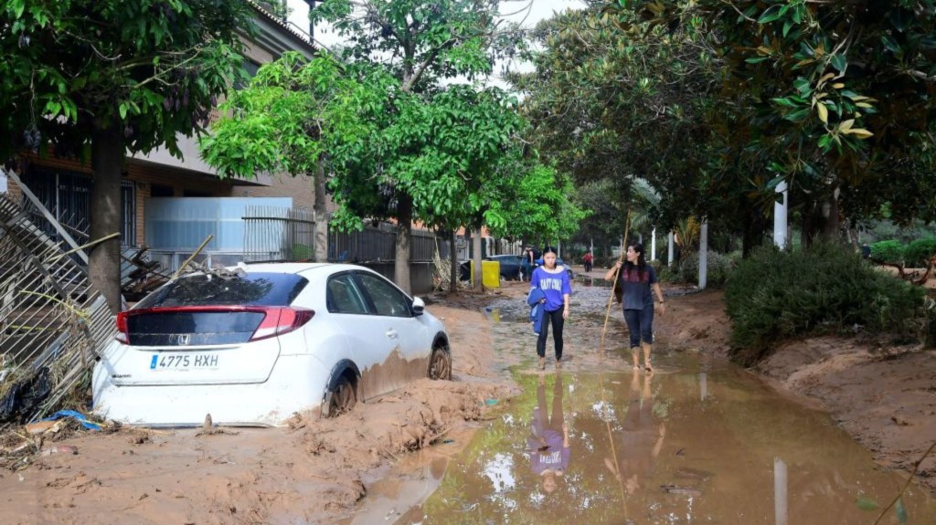 Personas caminan por una calle cubierta de lodo en una zona inundada en Picanya, cerca de Valencia, este de España, el 30 de octubre de 2024. (Foto: JOSE JORDAN/AFP vía Getty Images)