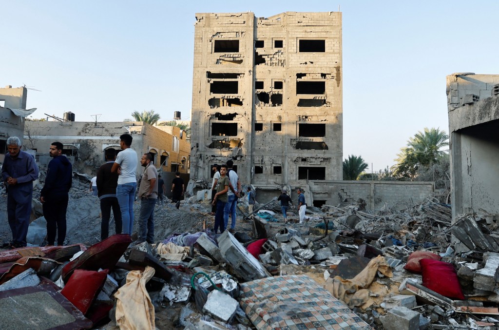Palestinos observan la destrucción de una casa tras un ataque en medio del conflicto con Israel en Khan Younis, sur de Gaza, el 12 de octubre de 2023. (Ibraheem Abu Mustafa/Reuters)