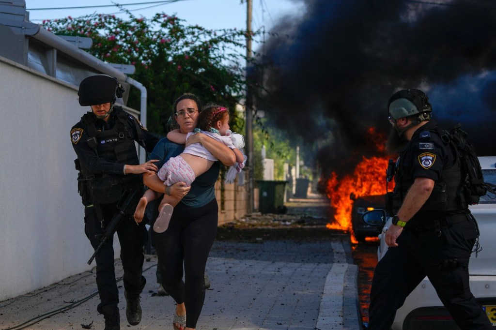 Agentes de policía evacúan a una mujer y un niño de un lugar alcanzado por un cohete en Ashkelon el 7 de octubre. (Crédito: Tsafrir Abayov/AP)