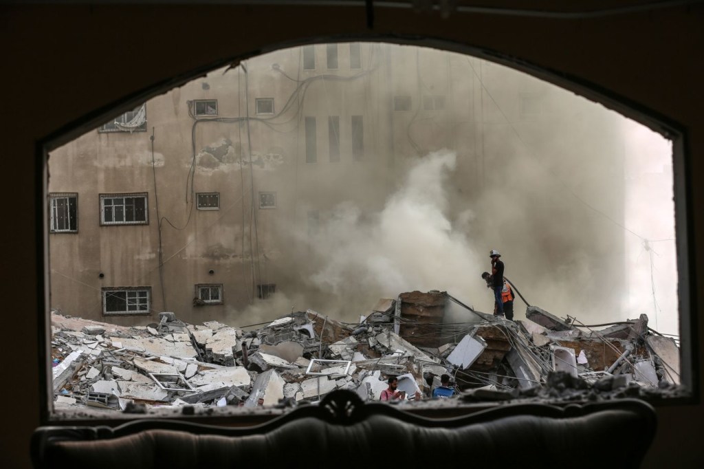 Palestinos inspeccionan un edificio destruido mientras los equipos de emergencia tratan de contener el fuego tras el bombardeo de Gaza por aviones israelíes el 7 de octubre. (Crédito: Samar Abu Elouf/The New York Times/Redux)