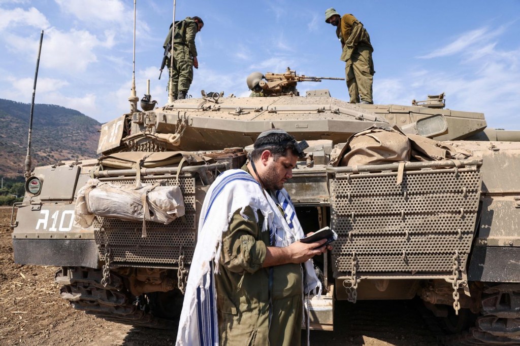 Un soldado israelí reza frente a un tanque en las afueras de la ciudad septentrional de Kiryat Shmona, el 8 de octubre. (Crédito: Jalaa Marey/AFP/Getty Images)