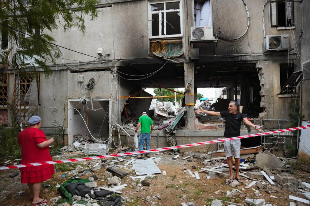 Israelíes observan un edificio residencial dañado en Ashkelon tras ser alcanzado por un cohete disparado desde Gaza el 9 de octubre. (Crédito: Erik Marmor/AAP)
