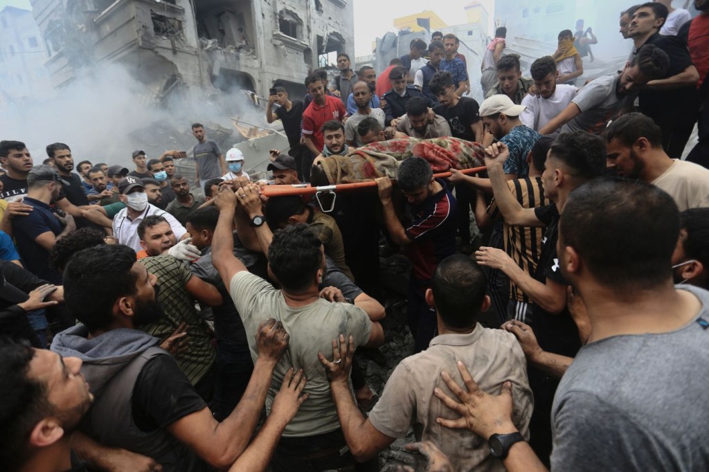 Palestinos retiran un cadáver de entre los escombros de un edificio tras un ataque aéreo israelí contra el campo de refugiados de Jebaliya, en Gaza, el 9 de octubre. (Crédito: Ramez Mahmoud/AP)