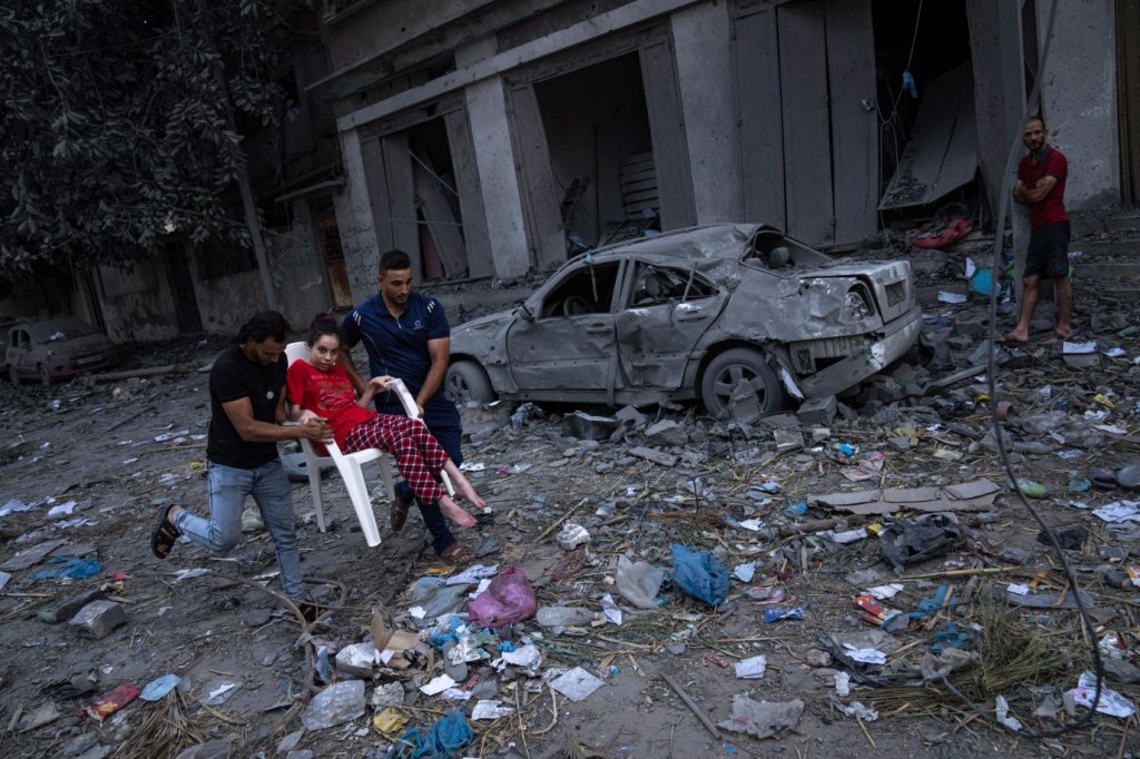 Palestinos pasan entre los escombros tras los ataques aéreos israelíes en la ciudad de Gaza el 10 de octubre. (Crédito: Fatima Shbair/AP)