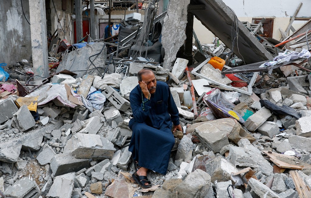 Un palestino sentado sobre los escombros de un edificio destruido por los ataques israelíes, en Rafah, sur de Gaza, el 9 de octubre de 2023. (Crédito: Ibraheem Abu Mustafa/Reuters)