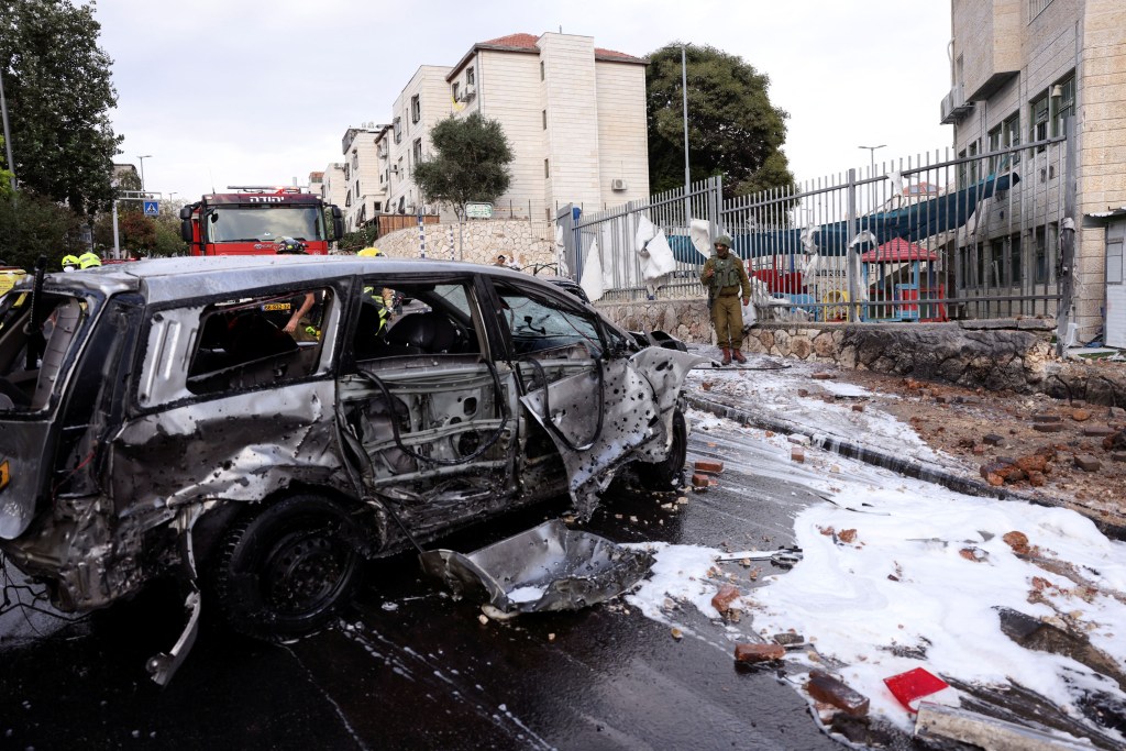 Los restos de un vehículo destruido se ven en una carretera después de que un cohete lanzado desde Gaza aterrizara en el asentamiento israelí de Beitar Ilit, en la Ribera Occidental ocupada por Israel, el 9 de octubre de 2023. (Crédito: Ronen Zvulun/Reuters)