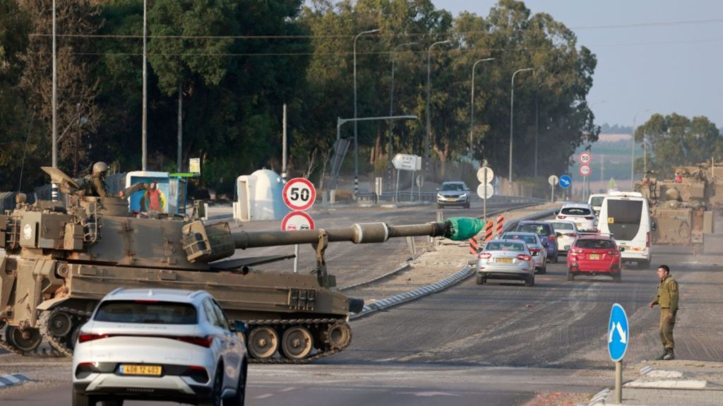 Las fuerzas israelíes cruzan una carretera principal en su obús autopropulsado mientras se despliegan tropas adicionales cerca de la ciudad sureña de Sderot el 8 de octubre de 2023. (Crédito: MENAHEM KAHANA/AFP vía Getty Images)