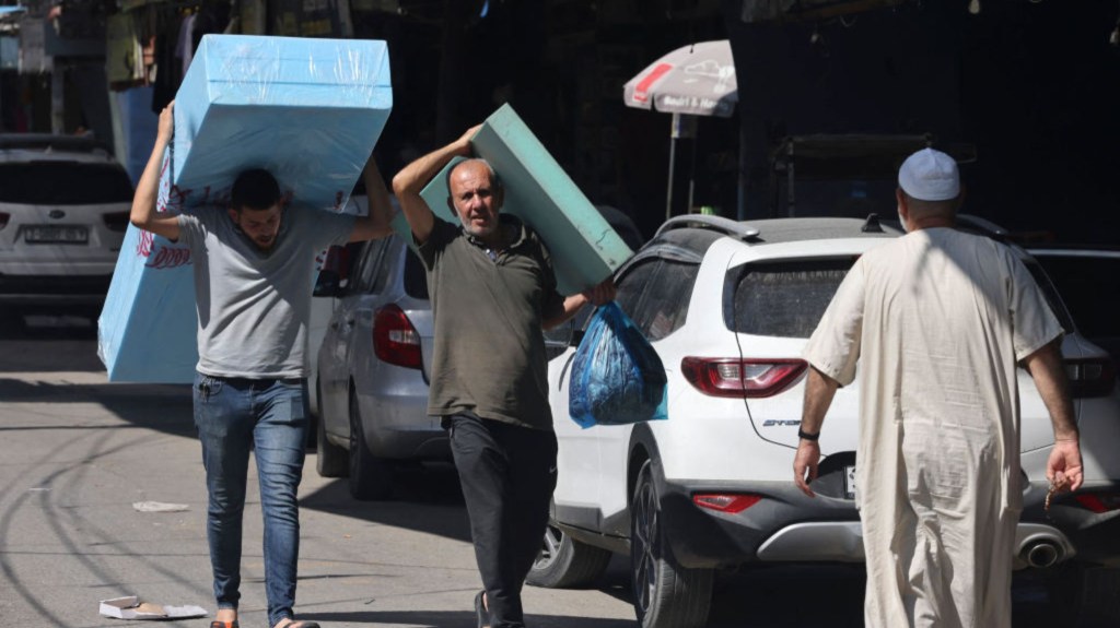 Palestinos llevan colchones a los desplazados de Gaza que llegan a su casa en el campo de refugiados de Rafah, al sur de Gaza, el 15 de octubre de 2023. (Crédito: MOHAMMED ABED/AFP vía Getty Images)