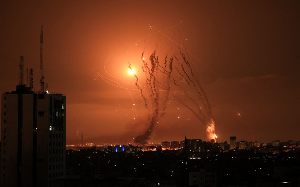 Militantes palestinos disparan una salva de cohetes desde Gaza mientras un misil israelí lanzado desde el sistema de misiles de defensa Domo de Hierro intenta interceptar los cohetes, disparados desde la Franja de Gaza, sobre la ciudad de Netivot en el sur de Israel el 8 de octubre de 2023. (Crédito: MAHMUD HAMS/AFP vía Getty Images)
