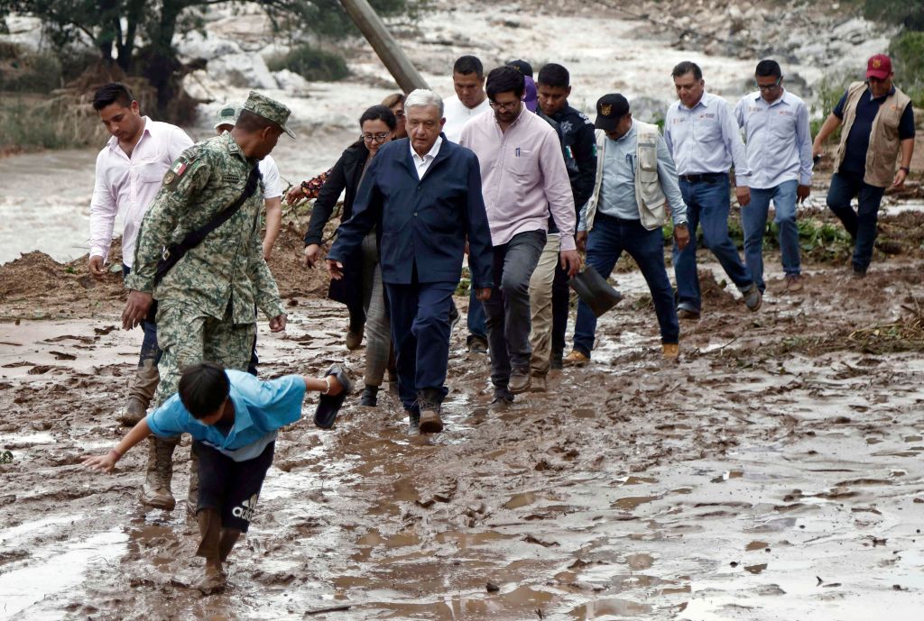 El presidente de México, Andrés Manuel López Obrador, y miembros de su gabinete caminan sobre el barro mientras visitan la comunidad del Kilómetro 42, cerca de Acapulco, Guerrero, México, después del paso del huracán Otis, el 25 de octubre de 2023. (Foto de RODRIGO OROPEZA/AFP vía Getty Images)