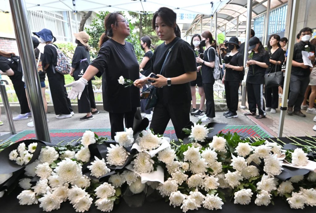 Personas depositan flores frente a un altar a un maestro de escuela primaria que murió en un aparente suicidio en julio en una escuela primaria en Seúl, el 4 de septiembre de 2023. (Jung Yeon-je/AFP/Getty Images)