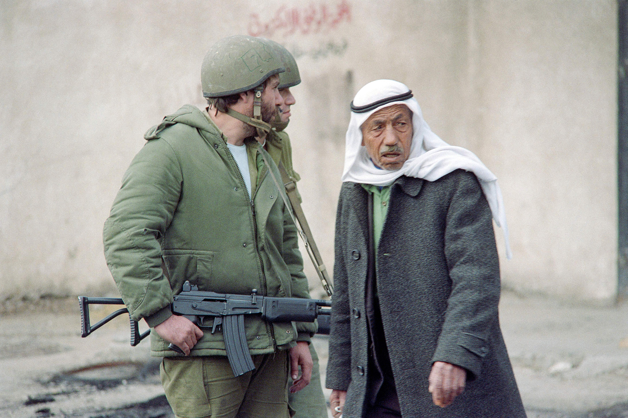 Un hombre palestino pasa junto a soldados israelíes que patrullan en una calle de Gaza el 20 de diciembre de 1987. (Esaias Baitel/AFP/Getty Images)